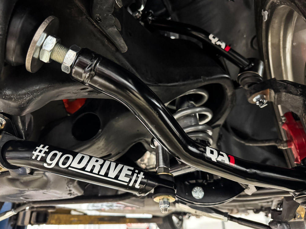 Close-up of the QA1 front suspension components, highlighting the control arms and coilovers.