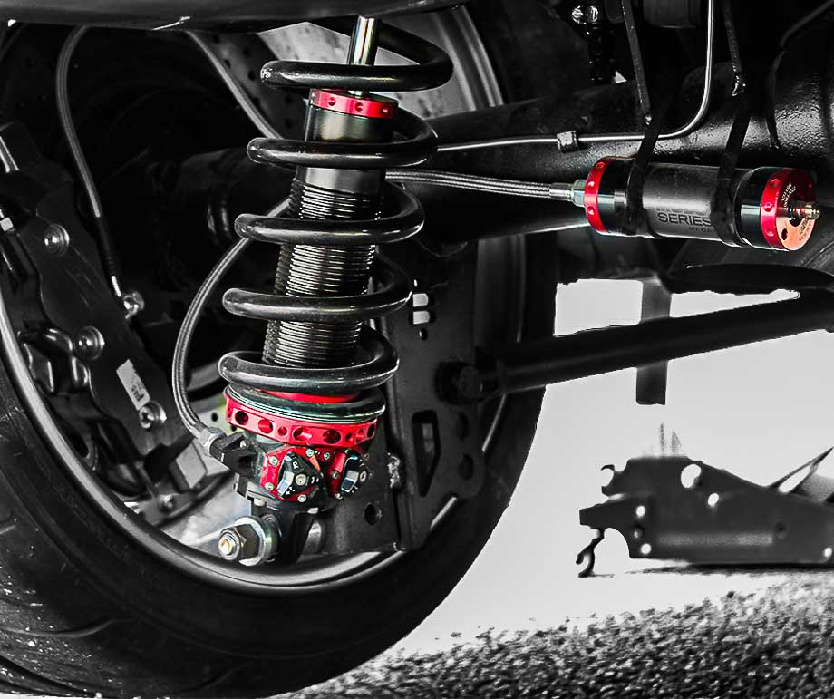 Close-up of QA1 MOD shocks’ modular valve packs and adjustment knobs, ideal for precision suspension tuning in drag racing and road courses.