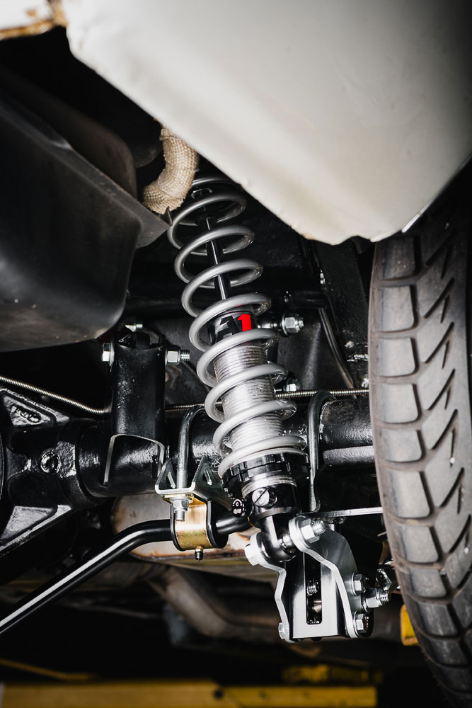 Close-up of upgraded coil-over shocks and springs installed on a Chevrolet Nova, providing adjustability for performance handling.